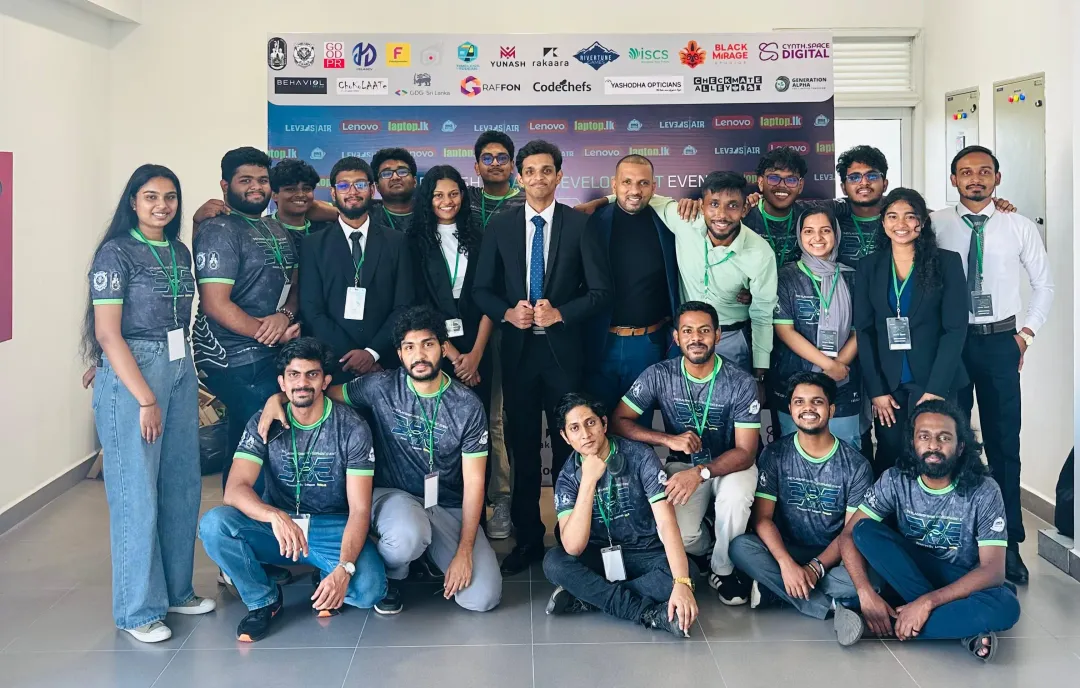 The EXE 2025 organizing committee, in matching green EXE shirts and formal wear, posing in front of a backdrop of partner logos